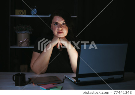 Young focused woman doing overtime job at night 77441348