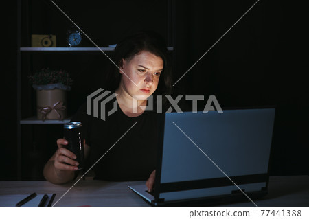 Focused woman drinking energy drink at night Focused woman drinking energy drink at night 77441388