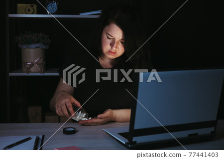 Tired woman taking pills during late night work 77441403
