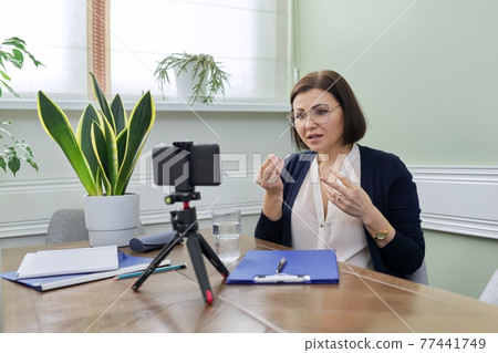 Mature confident woman counselor recording video stream, online consultation Mature confident woman counselor recording video stream, online consultation 77441749