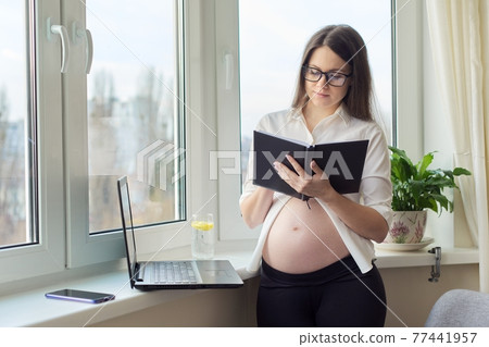 Pregnant business woman working at home with laptop, female writing in notebook 77441957