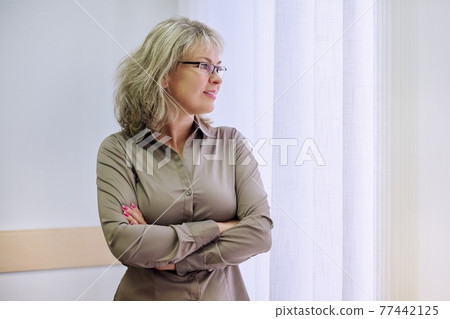 Portrait of mature confident business woman with crossed arms in office 77442125