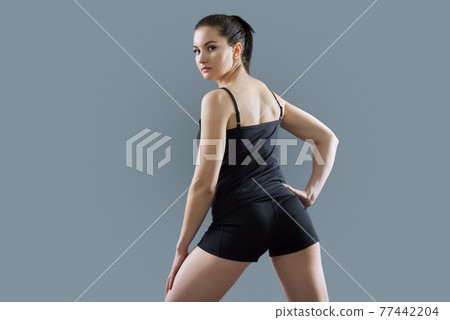 Athletic muscular woman body, model in sportswear posing on gray background Athletic muscular woman body, model in sportswear posing on gray background 77442204