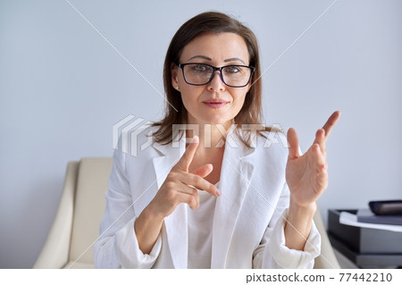 Positive talking middle aged business woman looking at webcam Positive talking middle aged business woman looking at webcam 77442210