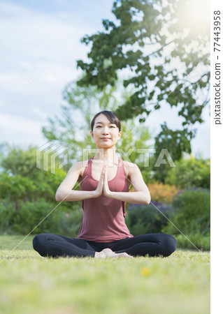 Young woman doing yoga in a green park 77443958
