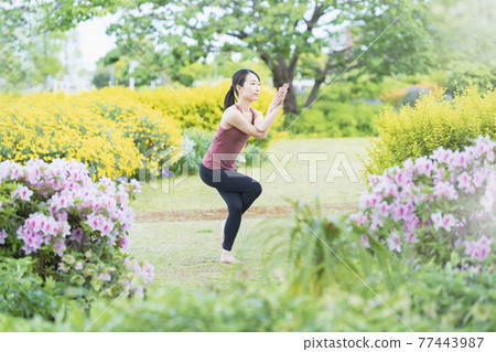 在綠色公園做瑜伽的年輕女子 77443987