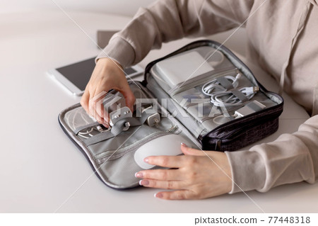 Top view female puts wires tablet modern electronic device equipment into comfortable storage bag 77448318