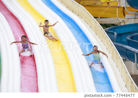 Children frolicking on the waterslide 77448477