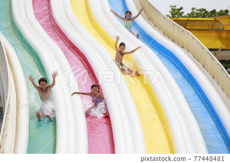 Children frolicking on the waterslide Children frolicking on the waterslide 77448481