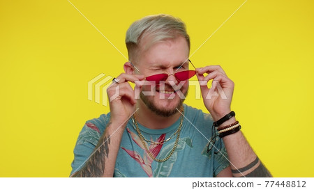 Playful happy man taking off sunglasses blinking eye looking at camera with smile, winking, flirting Playful happy man taking off sunglasses blinking eye looking at camera with smile, winking, flirting 77448812