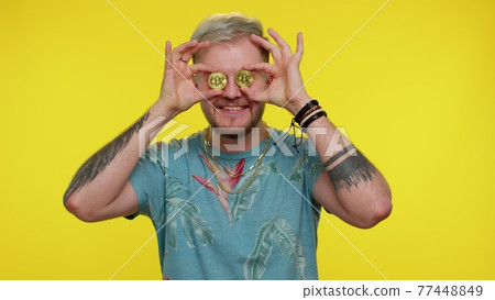 Handsome rich stylish tourist man fooling, showing golden bitcoins cryptocurrency investment, mining 77448849