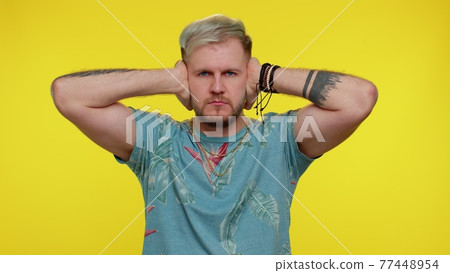 Frustrated irritated man covering ears, avoiding advice ignoring unpleasant noise loud voices 77448954