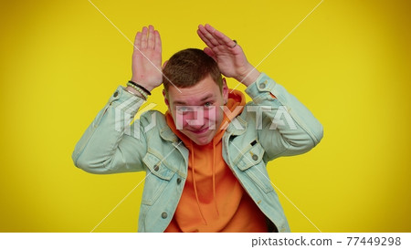 Lovely funny man smiling friendly, doing bunny ears gesture on head having fun fooling comical mood Lovely funny man smiling friendly, doing bunny ears gesture on head having fun fooling comical mood 77449298