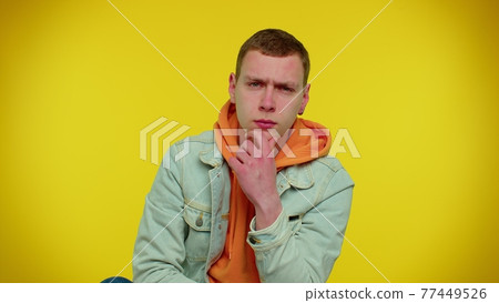 Thoughtful student man rubbing his chin with pensive expression, pondering a solution, question 77449526