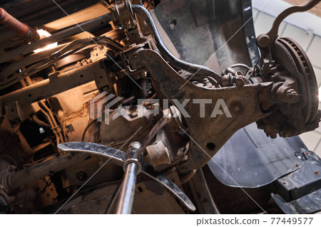 Inspects suspension, steering parts, tie rod ends. Car on a repair stand. Technical service station for car. Inspects suspension, steering parts, tie rod ends. Car on a repair stand. Technical service station for car. 77449577