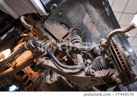 Inspects suspension, steering parts, tie rod ends. Car on a repair stand. Technical service station for car. Inspects suspension, steering parts, tie rod ends. Car on a repair stand. Technical service station for car. 77449578