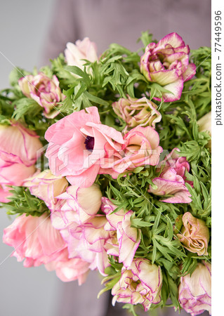 Beautiful bouquet of pink anemones in woman hand. the work of the florist at a flower shop. A small family business 77449596