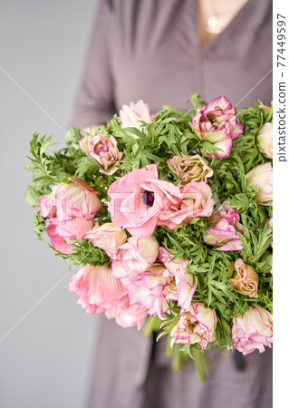 Beautiful bouquet of pink anemones in woman hand. the work of the florist at a flower shop. A small family business Beautiful bouquet of pink anemones in woman hand. the work of the florist at a flower shop. A small family business 77449597