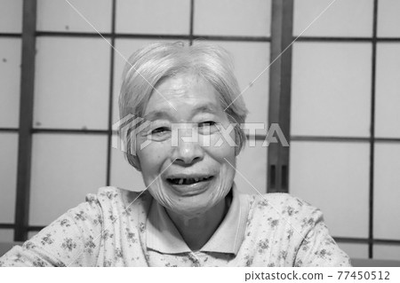 A happy smiling grandma sitting in front of a shoji window and wearing a rag shirt A happy smiling grandma sitting in front of a shoji window and wearing a rag shirt 77450512
