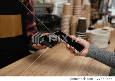 customer holding phone near nfc terminal make contactless payment. customer holding phone near nfc terminal make contactless payment. 77450557