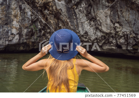 Woman tourist in boat on the lake Tam Coc, Ninh Binh, Viet nam. It's is UNESCO World Heritage Site, renowned for its boat cave tours. It's Halong Bay on land of Vietnam. Vietnam reopens borders after 77451569