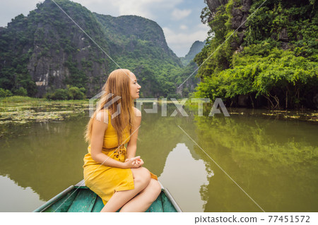 Woman tourist in boat on the lake Tam Coc, Ninh Binh, Viet nam. It's is UNESCO World Heritage Site, renowned for its boat cave tours. It's Halong Bay on land of Vietnam. Vietnam reopens borders after 77451572