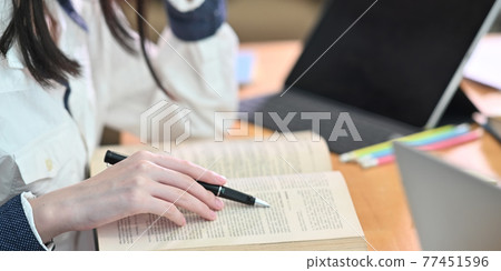 Cropped image of young woman tutoring her lesson while sitting in front her book and computer tablet with keyboard case that putting on cluttered working desk over comfort living room as background. 77451596