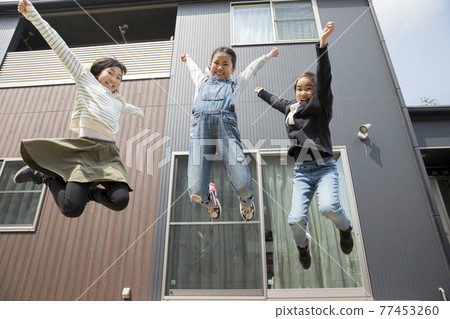 Elementary school girl jumping in front of the house 77453260