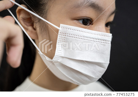 Asian child girl in a face mask,disease prevention campaign,wearing protective face masks before leaving home,in the city street,public,community,prevent contagious or spreading Coronavirus COVID-19 77453275