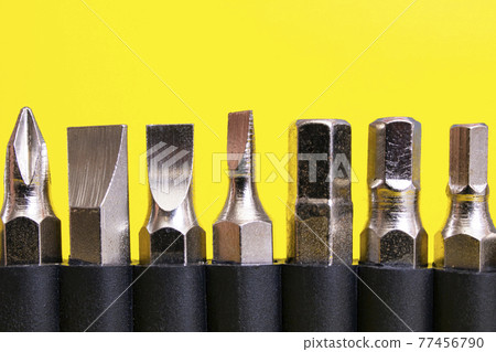 Screwdriver bits in a row on yellow background Screwdriver bits in a row on yellow background 77456790