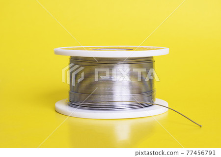 Metal wire spool on a yellow background Metal wire spool on a yellow background 77456791