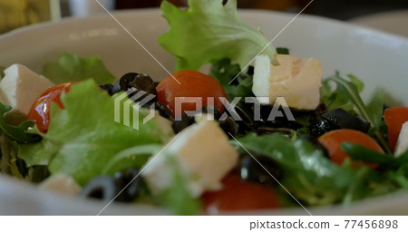 Tossing Greek salad before eating Tossing Greek salad before eating 77456898