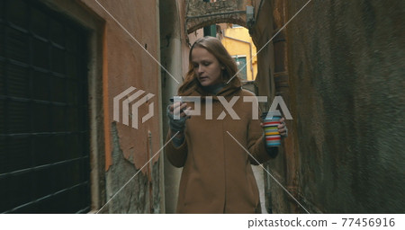 Woman with phone and coffee walking in Venice Woman with phone and coffee walking in Venice 77456916