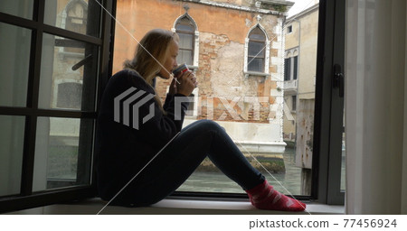 Woman with tea enjoying scene from the window Woman with tea enjoying scene from the window 77456924