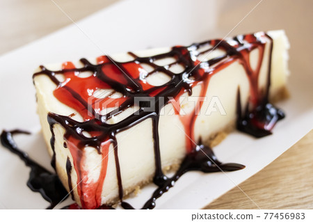 Cheesecake with raspberry and chocolate syrup on wooden table Cheesecake with raspberry and chocolate syrup on wooden table 77456983