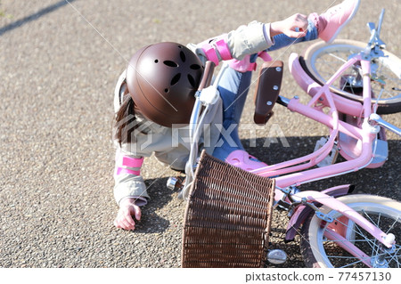 A girl who falls and gets injured while practicing a bicycle 77457130