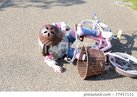 A girl who falls and gets injured while practicing a bicycle 77457131
