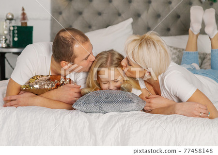 Beautiful young happy family on the new year's bed 77458148