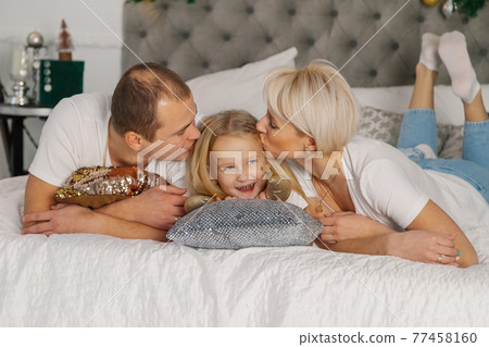 Beautiful young happy family on the new year's bed 77458160