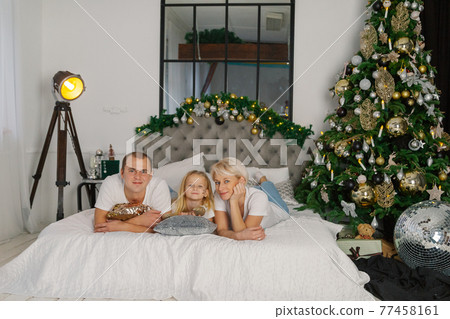 Beautiful young happy family on the new year's bed 77458161