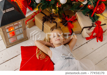 Beautiful little girl lies on the floor by the 77458170