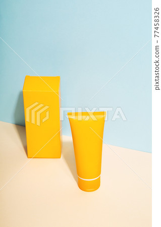Orange tube and box of sunscreen on blue background. Sun Protection. Copy space Orange tube and box of sunscreen on blue background. Sun Protection. Copy space 77458326