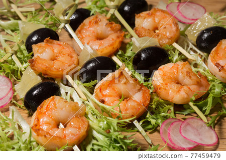 shish kebab from shrimps on black slate decorated with arugula and radish shish kebab from shrimps on black slate decorated with arugula and radish 77459479