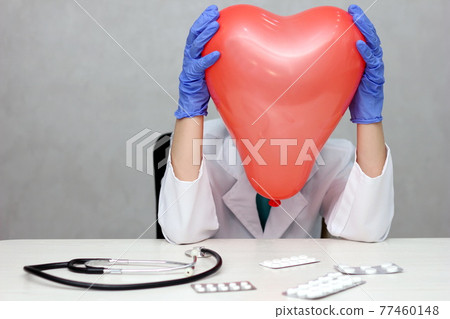 Cardiologist. The doctor holds his head in the shape of a heart. A tired cardiologist. Cardiology. 77460148