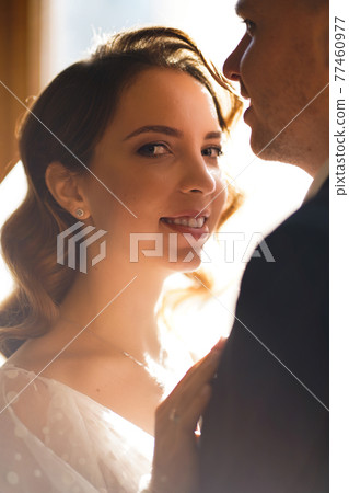 silhouettes of the bride and groom in sunlight through the glass in the door. silhouettes of the bride and groom in sunlight through the glass in the door. 77460977