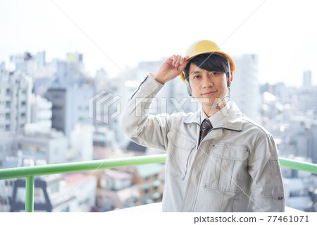 Men in work clothes putting their hands on the helmet 77461071