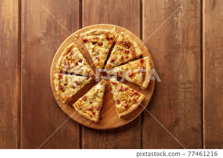 A quiche, shot from the top on a dark rustic wooden background A quiche, shot from the top on a dark rustic wooden background 77461216