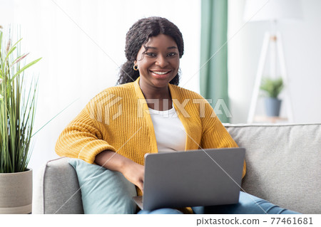 Cheerful young black woman freelancer working from home, using laptop Cheerful young black woman freelancer working from home, using laptop 77461681