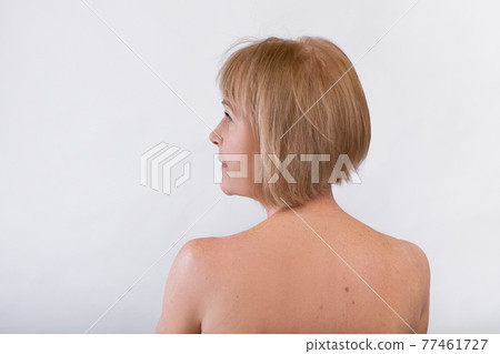 Back view of lovely mature woman with nude body looking aside on light studio background, free space Back view of lovely mature woman with nude body looking aside on light studio background, free space 77461727