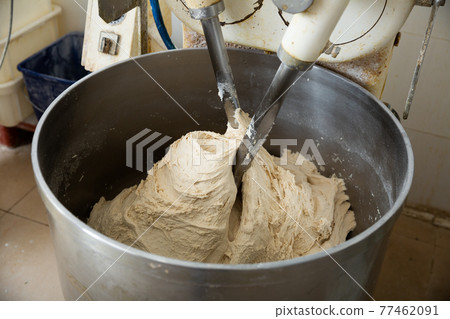Baker preparing the dough for bread in a dough mixer 77462091